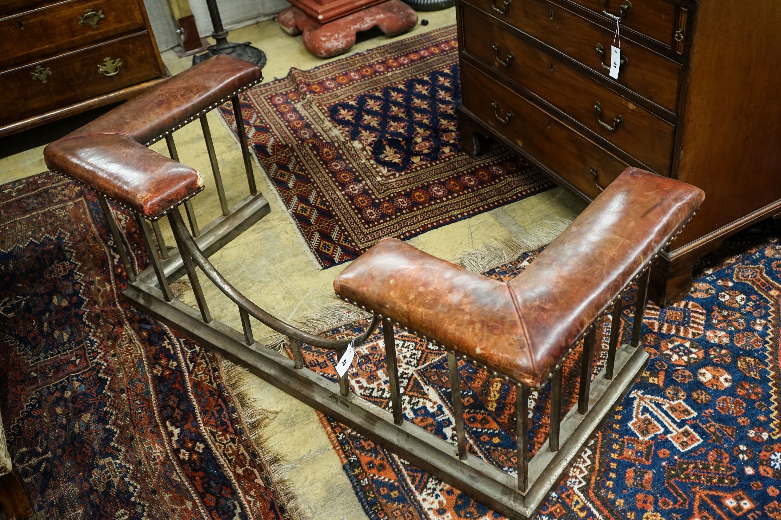 An early 20th century steel and burgundy leather club fender, length 140cm, depth 58cm, height 50cm